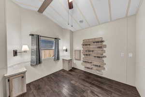 Unfurnished room with dark wood-style floors, lofted ceiling with beams, and a ceiling fan