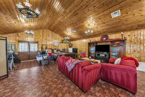 Living room with wood walls, french doors, a chandelier, and wood ceiling