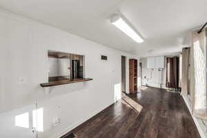 Empty room with dark wood-style flooring, crown molding, and wooden walls