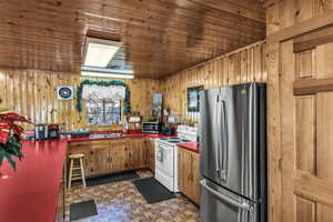 Kitchen featuring stainless steel appliances, dark floors, wood walls, and wood finish cabinetry