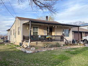 Bungalow featuring covered porch, a chimney, a garage, and a front yard
