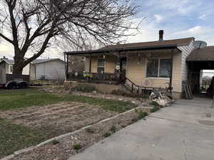 Bungalow-style home with a porch, a chimney, a front lawn, and roof with shingles