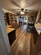 Kitchen with dark wood-style floors, ceiling fan, gas stove, light countertops, and dark wood finish cabinets