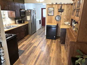 Kitchen with black appliances, dark wood finish cabinets, light countertops, and light wood-type flooring