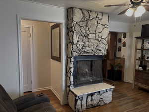 Living area with ceiling fan, a fireplace, and dark wood-type flooring