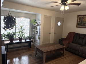 Living room with dark wood finished floors and ceiling fan