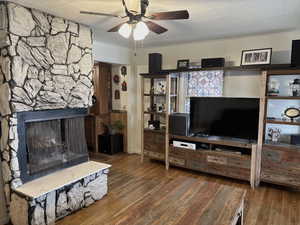Living area featuring a fireplace, a ceiling fan, and dark wood-style floors