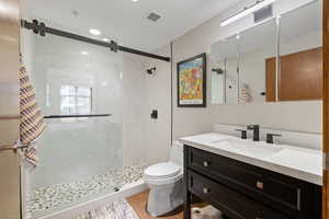 Full bathroom featuring a marble finish shower, vanity, and light wood-type flooring