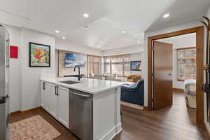 Kitchen with a peninsula, stainless steel appliances, open floor plan, dark wood-style floors, and white cabinets