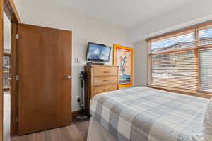 Bedroom featuring dark wood-style flooring and baseboards