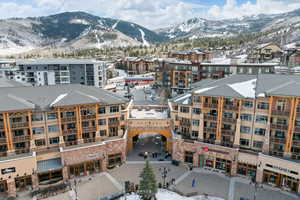 Snowy aerial view with a mountain view and a view of apartment building / complex