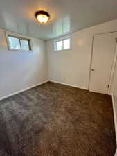 Basement with dark colored carpet and baseboards