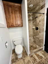 Full bathroom featuring a shower stall and stone finish floors