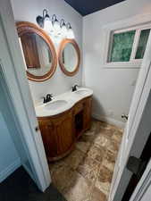 Bathroom with double vanity and stone finish flooring