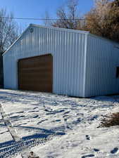 Snow covered garage with a detached garage