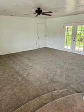 Unfurnished room featuring french doors, dark colored carpet, ceiling fan, and a textured ceiling