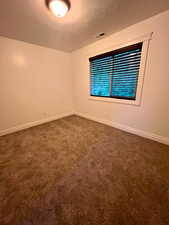 Unfurnished room featuring dark carpet and a textured ceiling