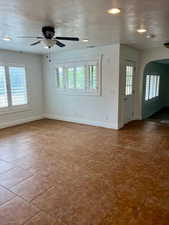 Empty room with arched walkways, healthy amount of natural light, a ceiling fan, a textured ceiling, and recessed lighting