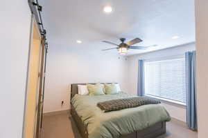 Bedroom with a barn door, light colored carpet, recessed lighting, and ceiling fan