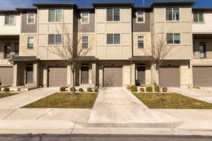 View of front of home with a balcony, stone siding, and driveway