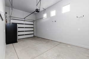 Third garage bay featuring baseboards and a garage door opener