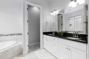 Primary bathroom featuring a bath, double vanity, and light tile patterned floors