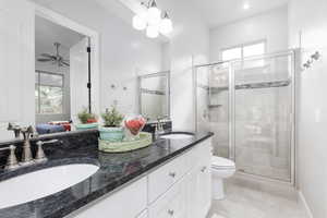Ensuite bathroom with double vanity, a shower stall, a ceiling fan, and light tile patterned flooring