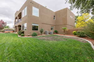 Rear view of property with stucco siding, a balcony, and a hot tub