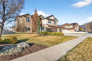 View of front facade featuring stone siding, concrete driveway, an attached garage, and stucco siding
