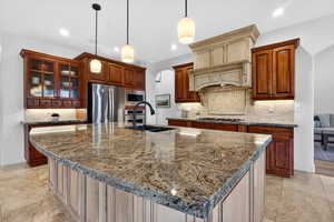 Kitchen with arched walkways, pendant lighting, decorative backsplash, stainless steel appliances, and dark stone counters