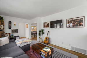 Living area featuring arched walkways and wood finished floors