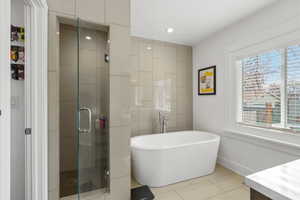 Full bath featuring a stall shower, a freestanding tub, light tile patterned floors, vanity, and recessed lighting