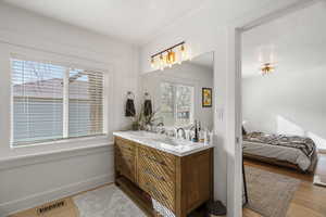 Ensuite bathroom with double vanity and light wood-style flooring
