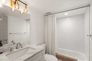 Bathroom featuring vanity and shower / bathtub combination with curtain