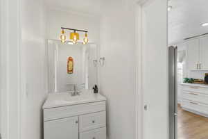 Bathroom with vanity, a textured ceiling, light wood-type flooring, and recessed lighting