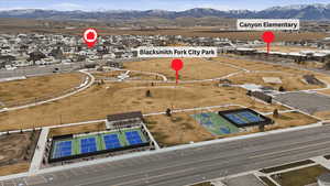 Aerial view of property and surrounding area featuring a mountainous background and nearby suburban area