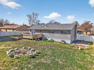 Back of house featuring a fenced backyard, a chimney, a wooden deck, brick siding, and a gate