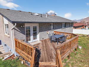 Deck with outdoor dining space, french doors, and a mountain view