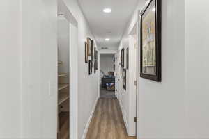 Hallway with light wood finished floors and recessed lighting