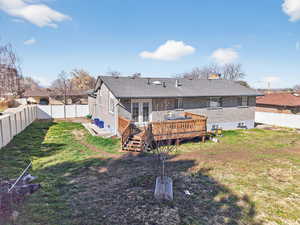 Rear view of property featuring a fenced backyard, brick siding, a wooden deck, a chimney, and french doors