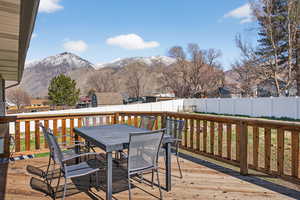 Wooden terrace featuring a fenced backyard, a mountain view, and outdoor dining space