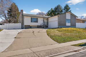 View of front of house featuring concrete driveway, brick siding, a gate, a chimney, and a mountain view
