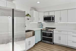 Basement Kitchen with stainless steel appliances, white cabinets, light wood-style flooring, open shelves, and recessed lighting