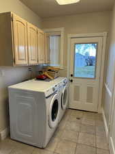 Laundry area featuring washing machine and dryer, a textured ceiling, and cabinet space