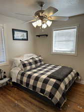 Bedroom featuring dark wood-style floors, ceiling fan, and a textured ceiling