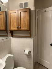 Half bathroom with light tile patterned floors and tile walls