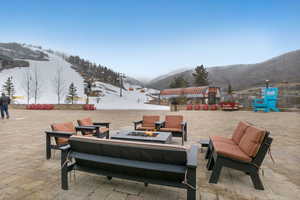 Snow covered patio featuring a patio, a mountain view, and an outdoor fire pit