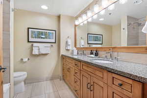 Bathroom with large vanity, light tile patterned floors, granite countertops and a tile shower