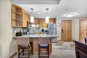 Kitchen with a kitchen breakfast bar, a peninsula, backsplash, stainless steel appliances, and open shelves