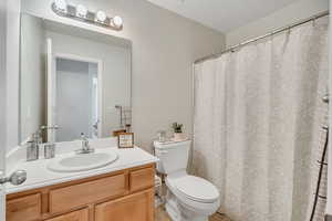 Full bath featuring vanity, curtained shower, a textured ceiling, and light tile patterned floors